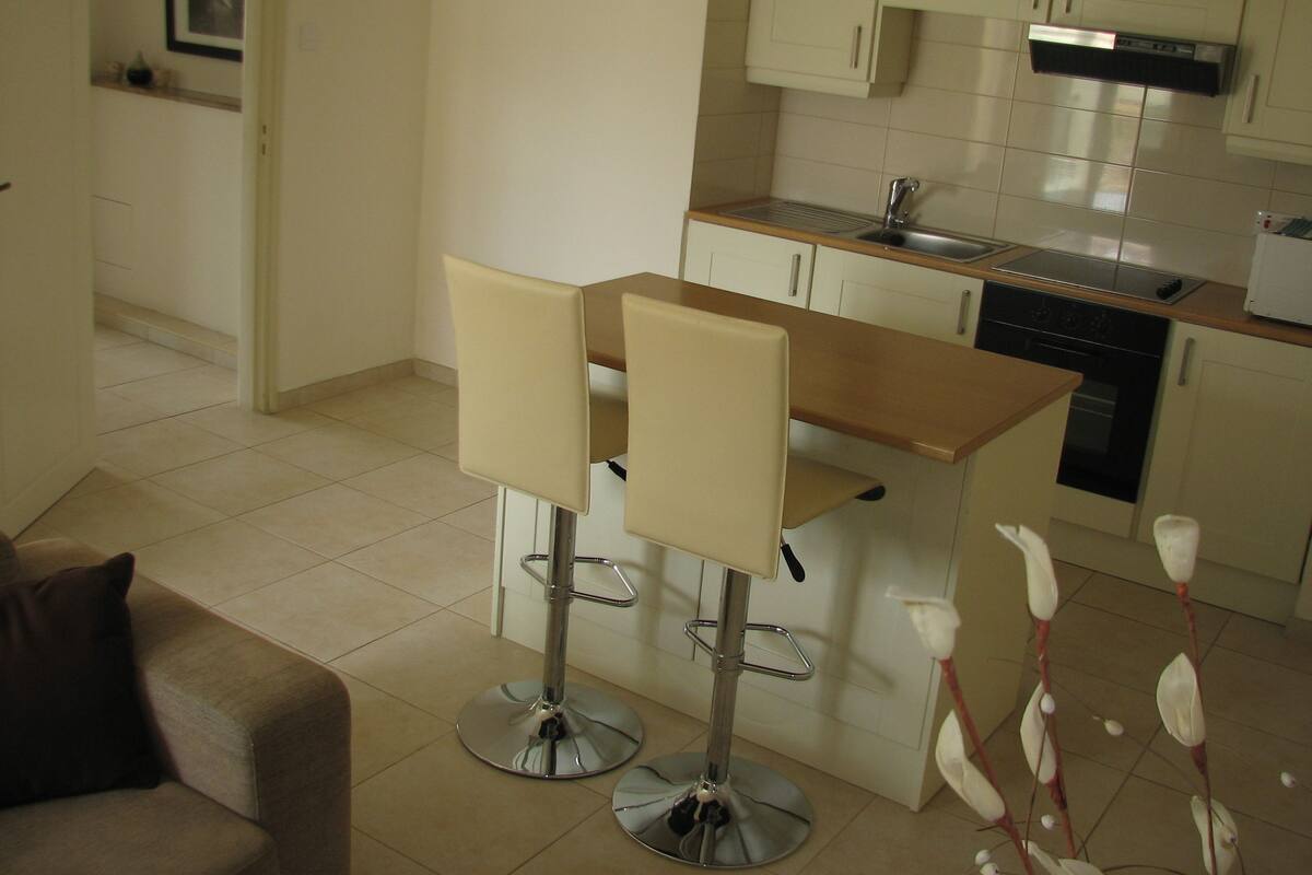 A compact kitchen with a dining area, including a small island and two bar stools.