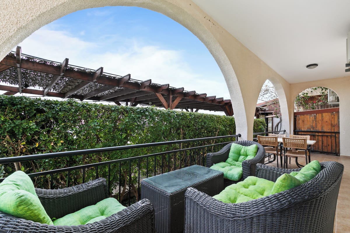 An outdoor patio with wicker furniture and a pergola.
