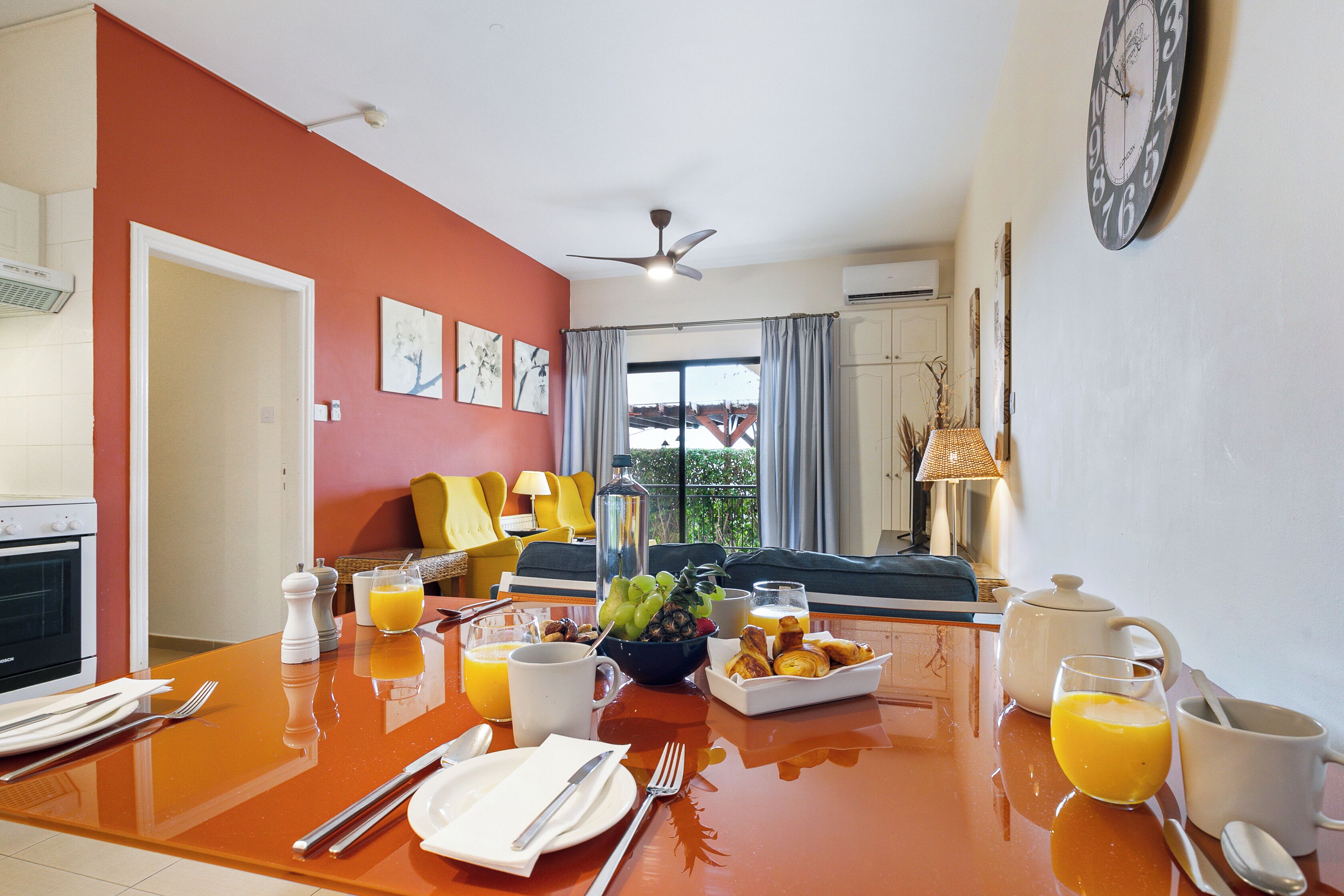 A breakfast table set with plates, utensils, and a fruit bowl.