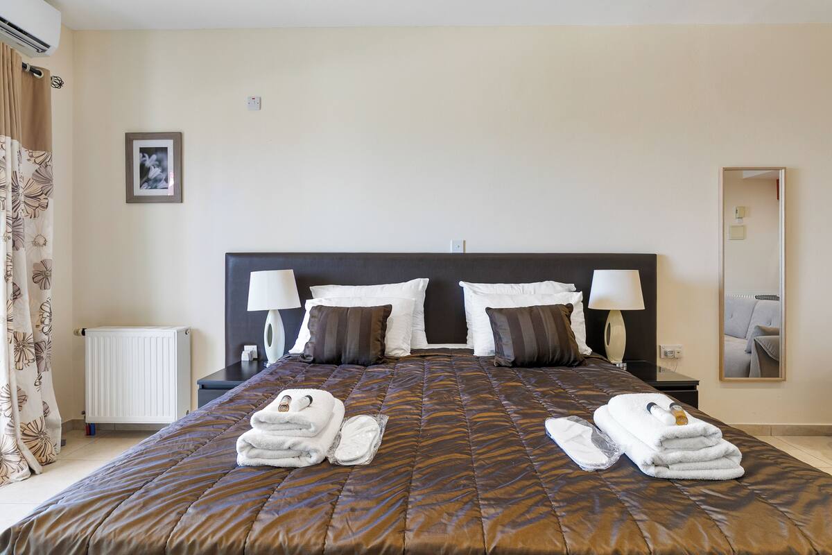 A hotel room with a large bed, two bedside tables with lamps, a radiator, a framed picture on the wall, and a mirror on the wall.