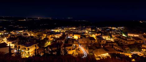 Vista nocturna de un pueblo con edificios iluminados y una carretera serpenteante.