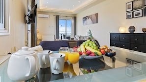 A modern hotel room with a dining area featuring a breakfast setup including a teapot, cups, and a fruit bowl. - Hill View Restaurant & Apartments (Pissouri)