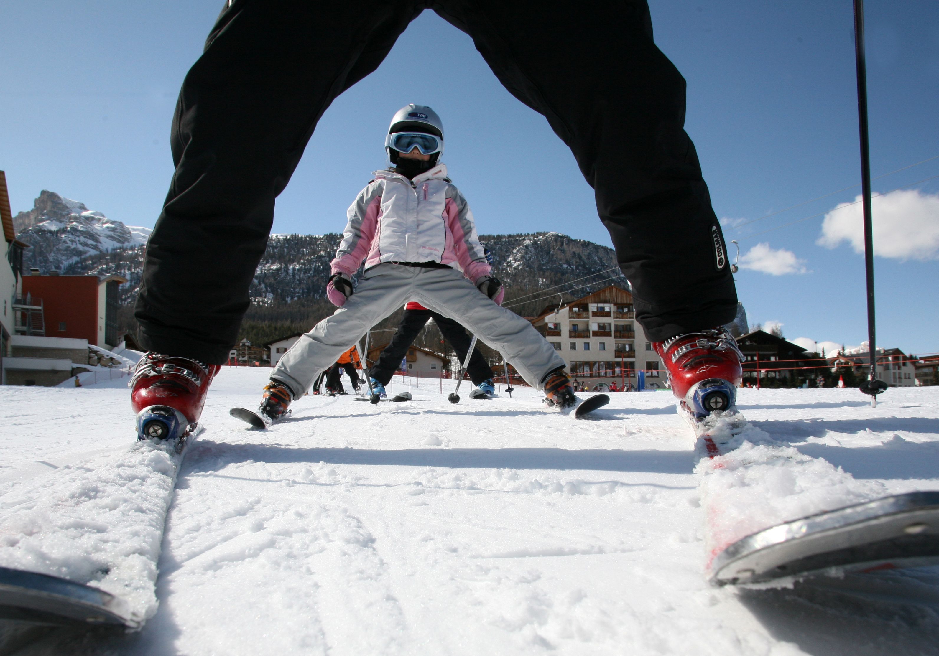 Ein verschneiter Ski-Hang im Vordergrund mit Skifahrern und ein Berg im Hintergrund.
