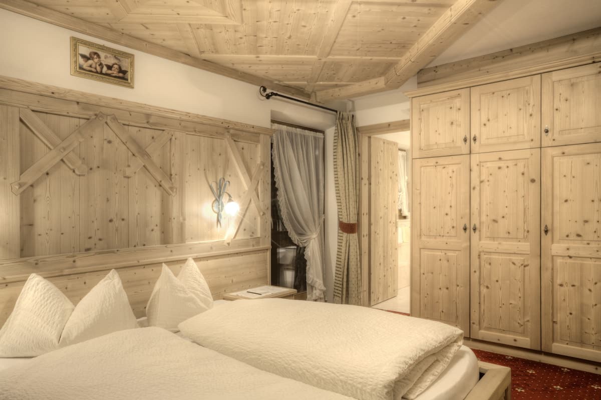 A bedroom with wooden paneling, a bed with white bedding, and a wardrobe.