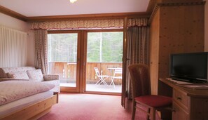 Relax in this serene bedroom with a large bed, desk, and TV, perfect for work or unwinding. Enjoy the view of the surrounding forest from the large window.