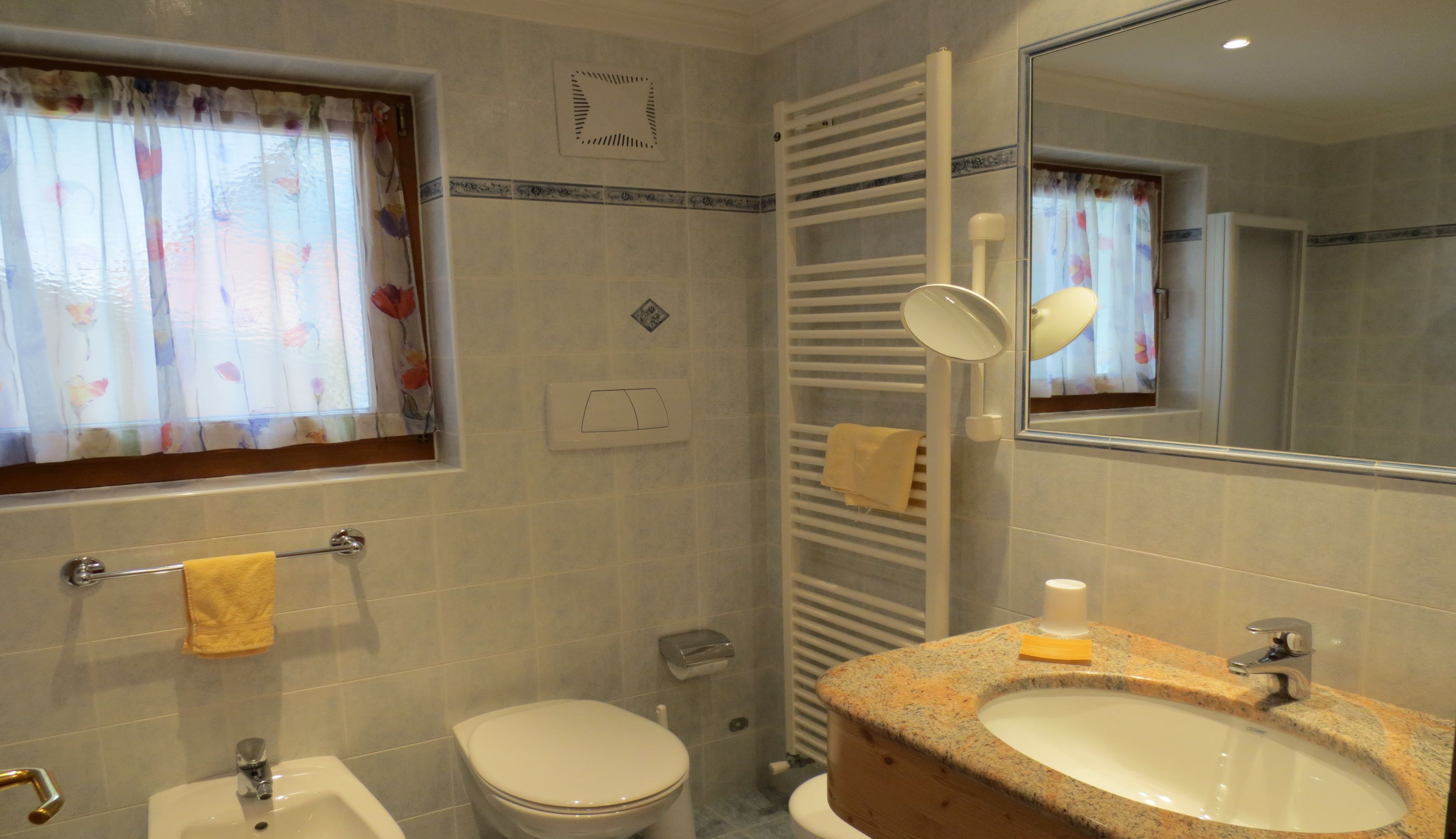 A bathroom with a toilet, sink, and mirror.