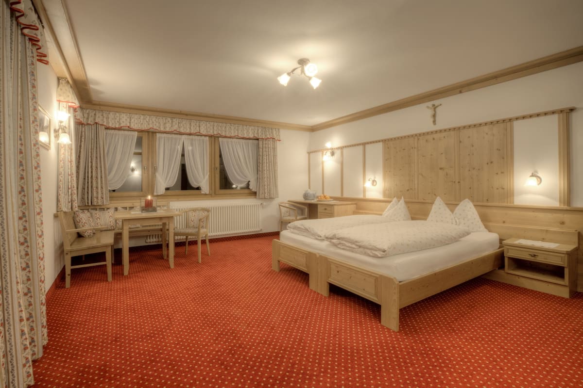 A bedroom with a wooden bed, a desk, a chair, and a radiator.