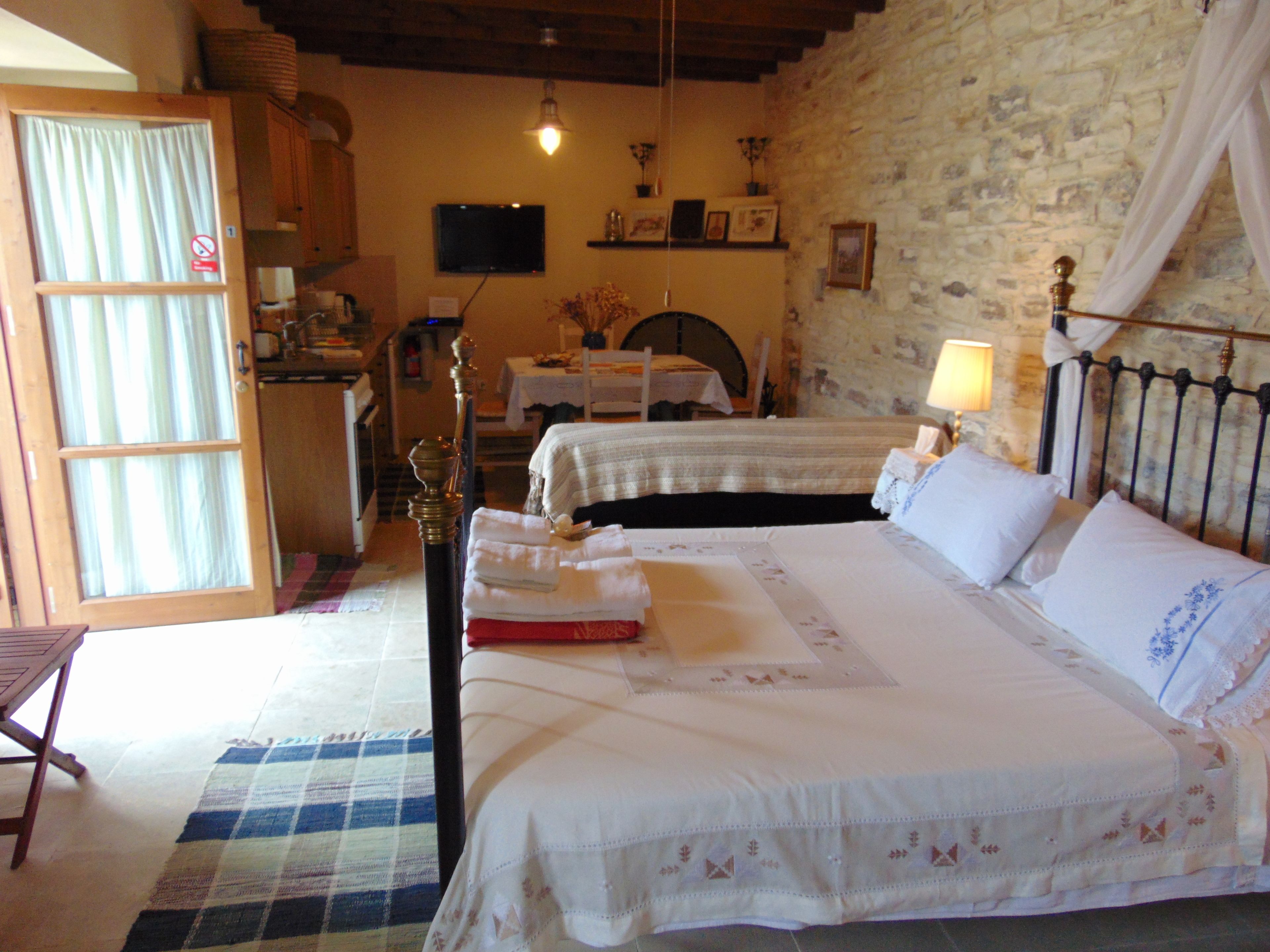 A bedroom with two beds, a dining area, and a kitchen.