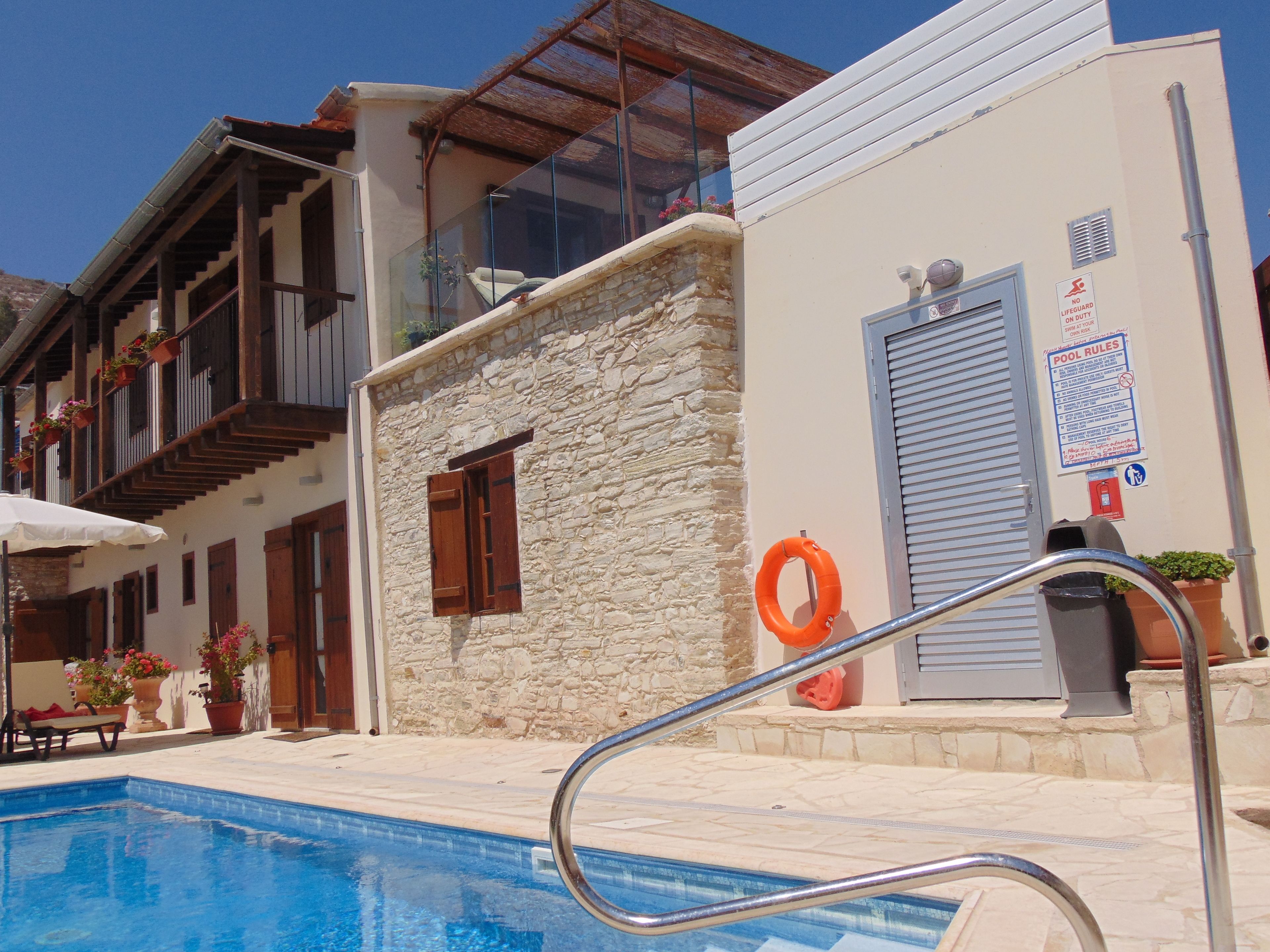 A pool area with a stone building, wooden balconies, and a lifebuoy.