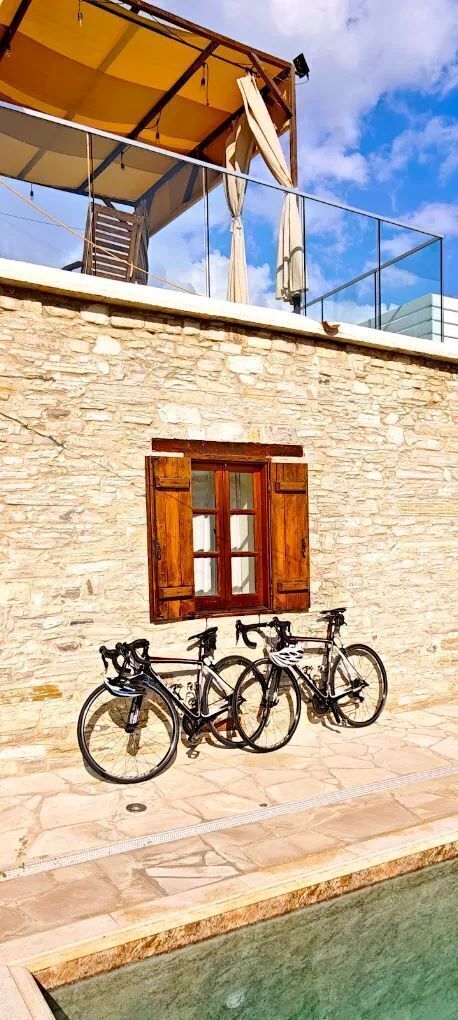 A stone building with a window, a balcony with a yellow awning, and bicycles parked outside.