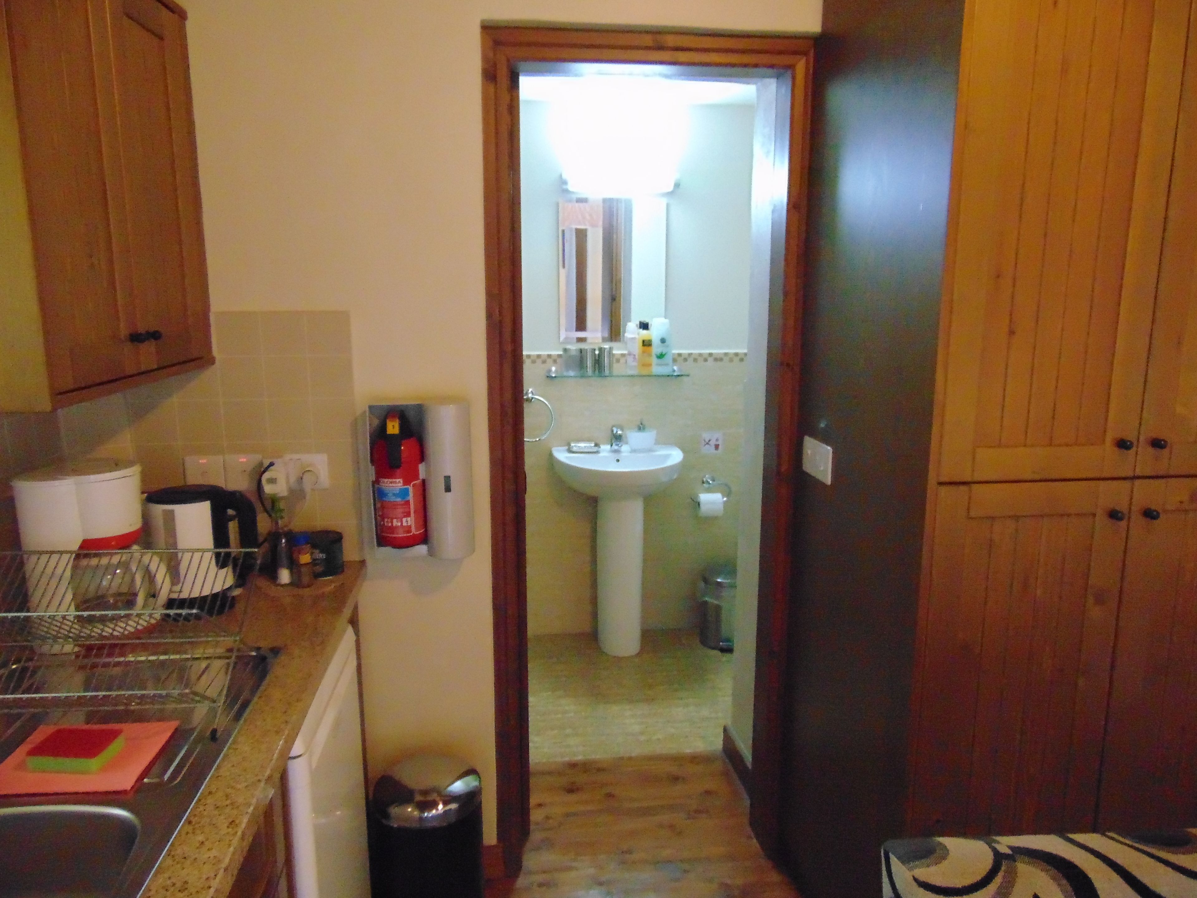 A kitchen with wooden cabinets, a sink, and a countertop with a dish rack and a coffee maker.