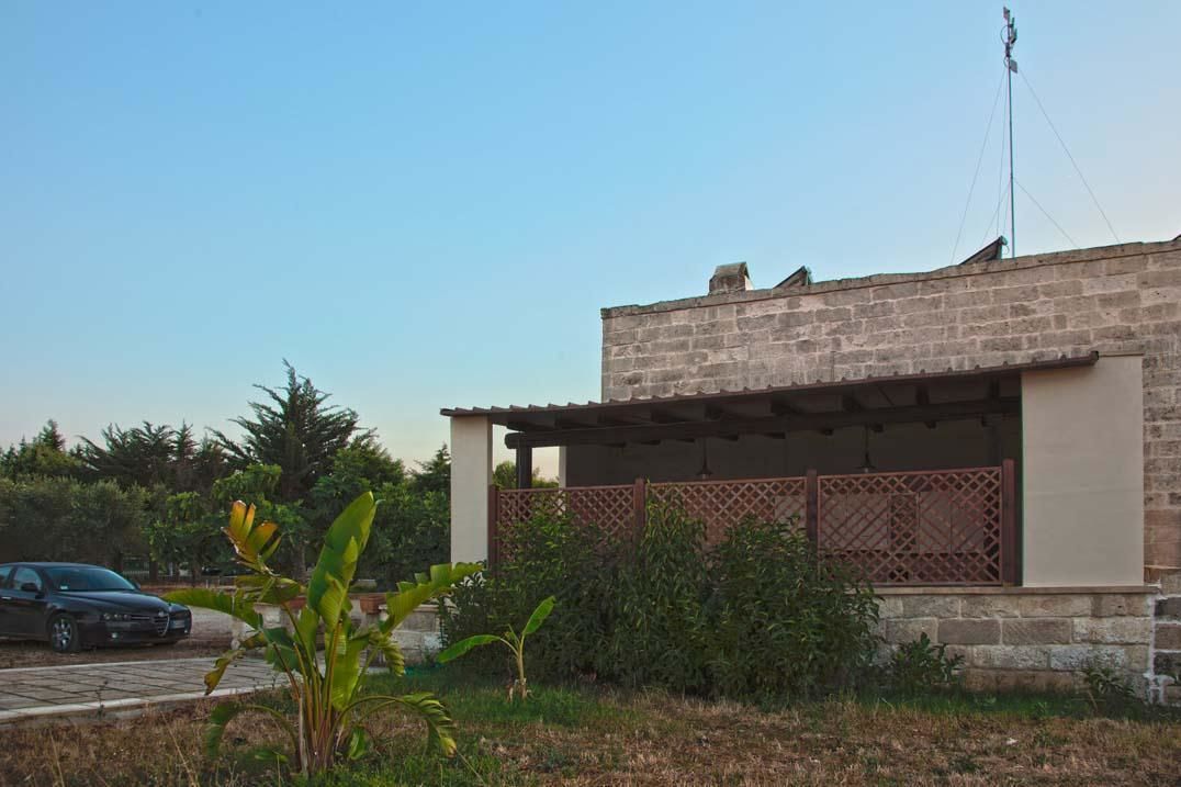 A stone building with a covered porch and a car parked in front.