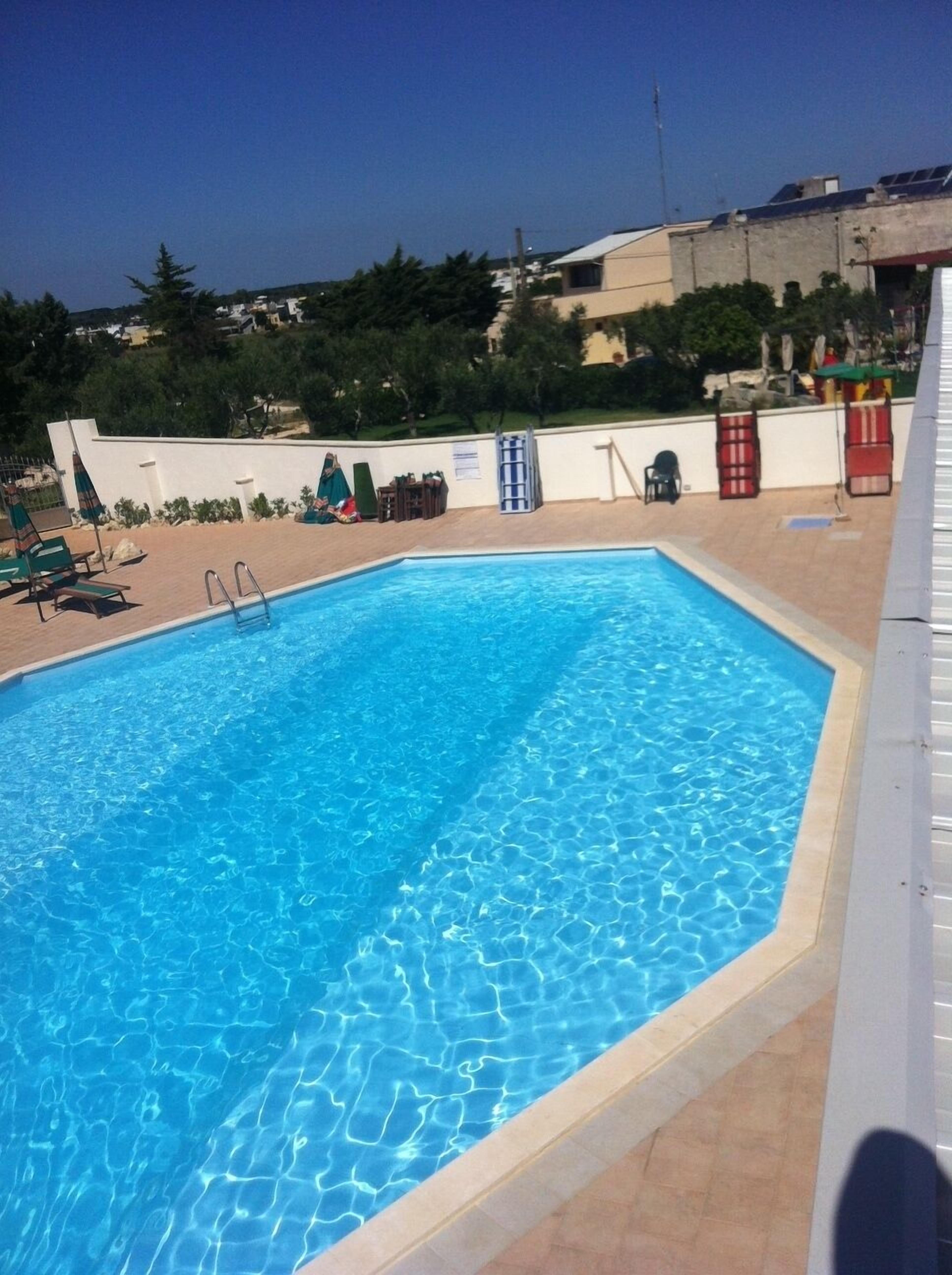 Une piscine rectangulaire à l’eau d’un bleu cristallin, entourée d’une terrasse carrelée.