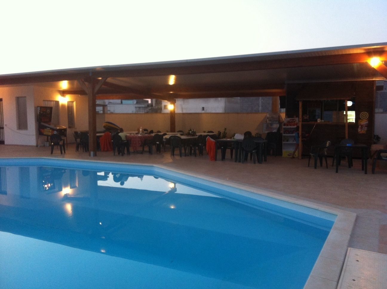 An outdoor swimming pool with a covered seating area and tables.