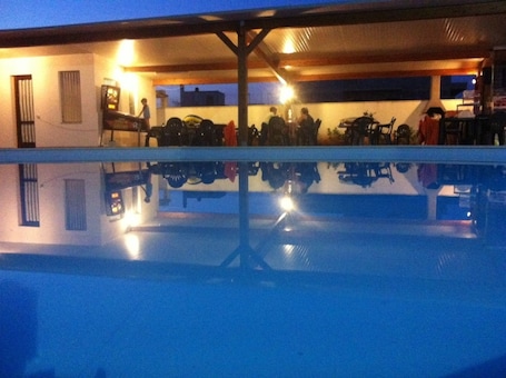 Una piscina al aire libre, sombrillas, sillones reclinables de piscina