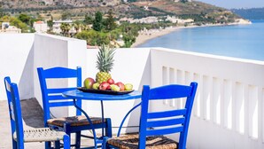 A table with chairs and a fruit bowl on a balcony overlooking a beach. - Kalyves Bay (Apokoronas)