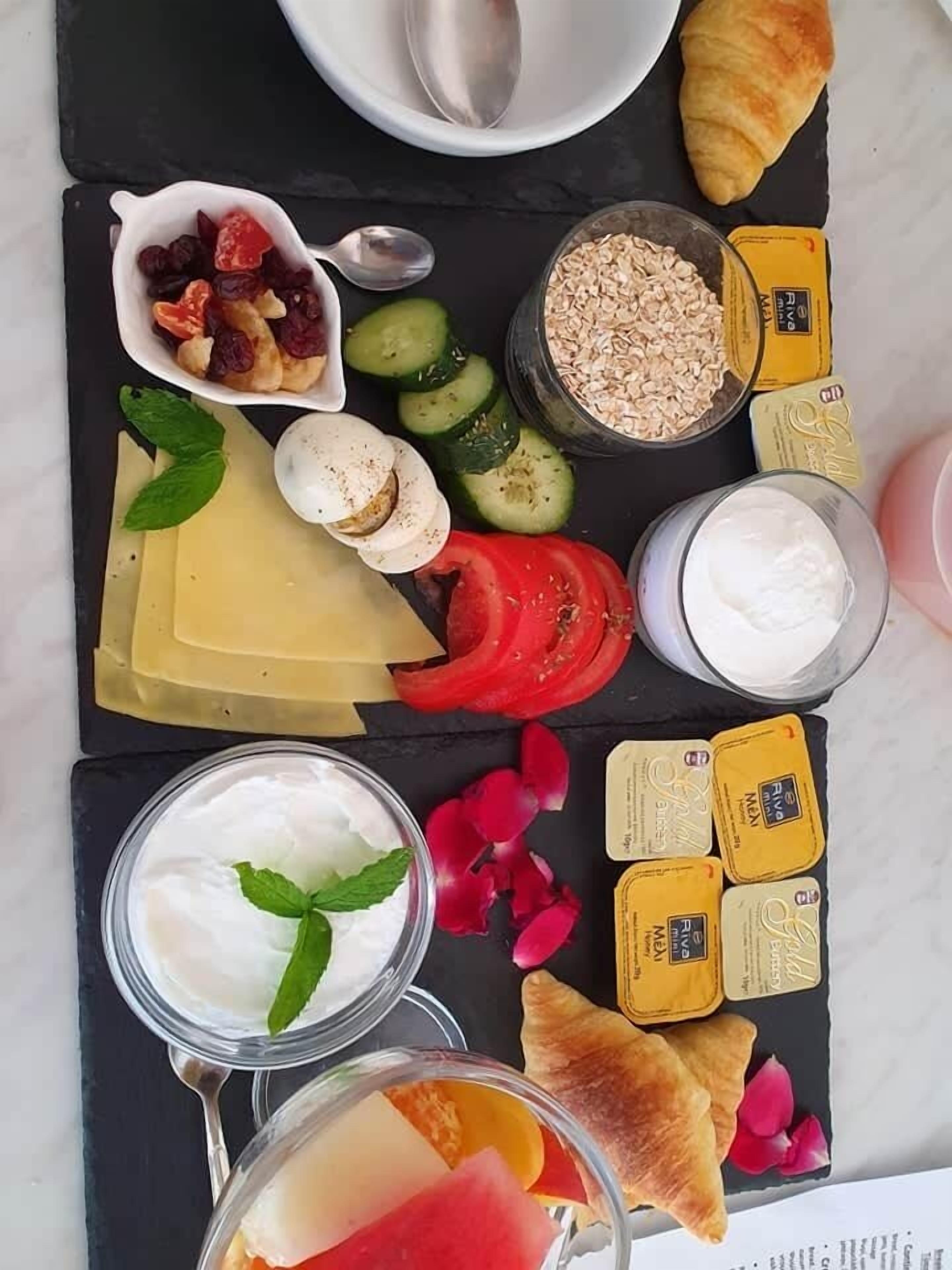 A variety of food items including cheese, yogurt, and fruits arranged on a black slate board.