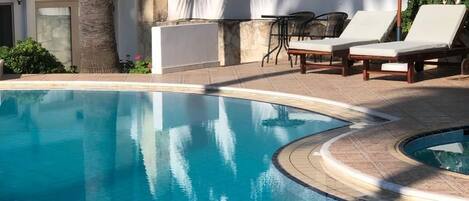 A swimming pool with lounge chairs and a wall with a sign.