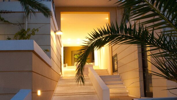 A staircase leading to a building entrance with a palm tree on the right. - Elizabeth Suites (Chania)