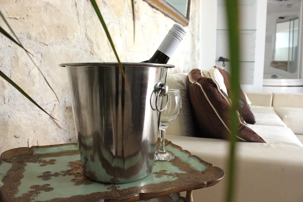 Un seau en métal, une bouteille, un verre et un plateau décoratif sont posés sur une table.