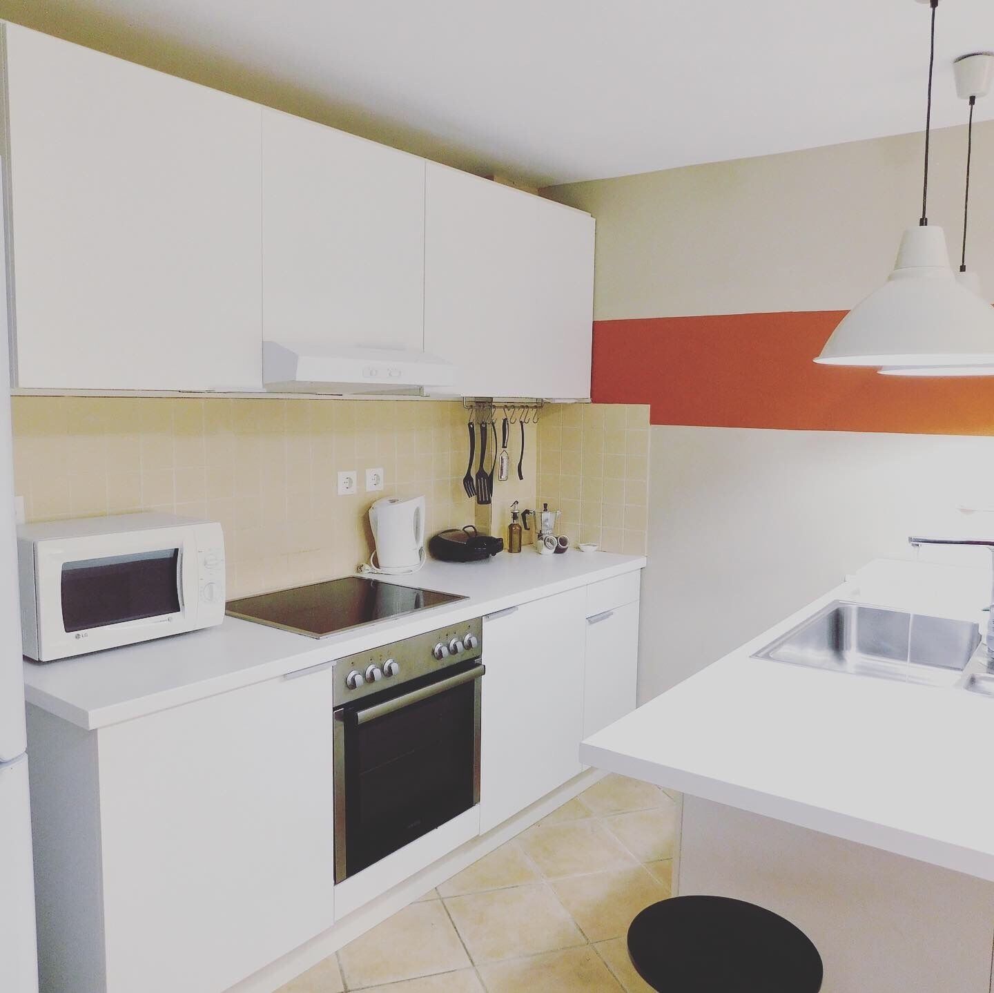 A compact kitchen with white cabinets, a microwave, stove, and sink.