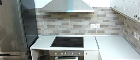 A compact kitchen with a stainless steel range hood, a built-in oven, and a sink.