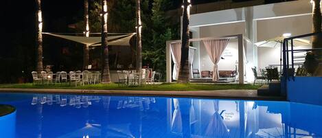 Een buitenzwembad, parasols bij het zwembad en ligstoelen