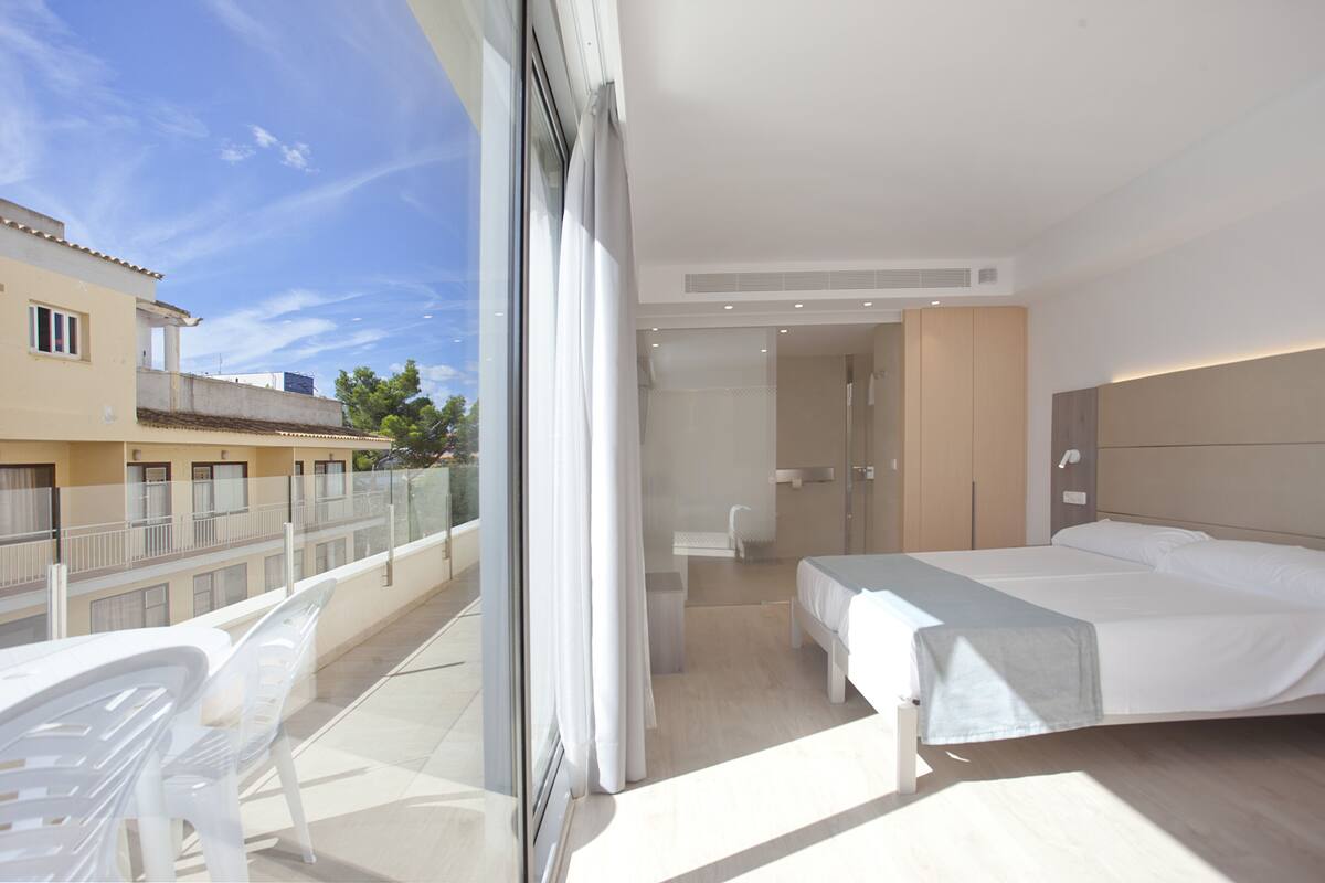 Ein modernes Hotelzimmer mit Balkon, Bett, Bad und Blick auf die Stadt.