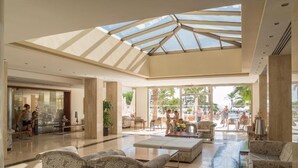 A spacious lobby with patterned sofas, a central coffee table, and a skylight. - Aparthotel Playa Dorada (Sant Llorenc des Cardassar)
