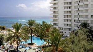 A hotel with a pool, palm trees, and a view of the ocean. - Aparthotel Playa Dorada (Sant Llorenc des Cardassar)