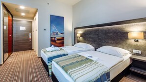 A hotel room with two beds, a painting on the wall, a headboard with built-in lighting, and a carpeted floor. - ETO Park Hotel Business & Stadium (Gyor)
