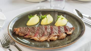 Um prato com bife e duas batatas cozidas sobre um prato de cerâmica.