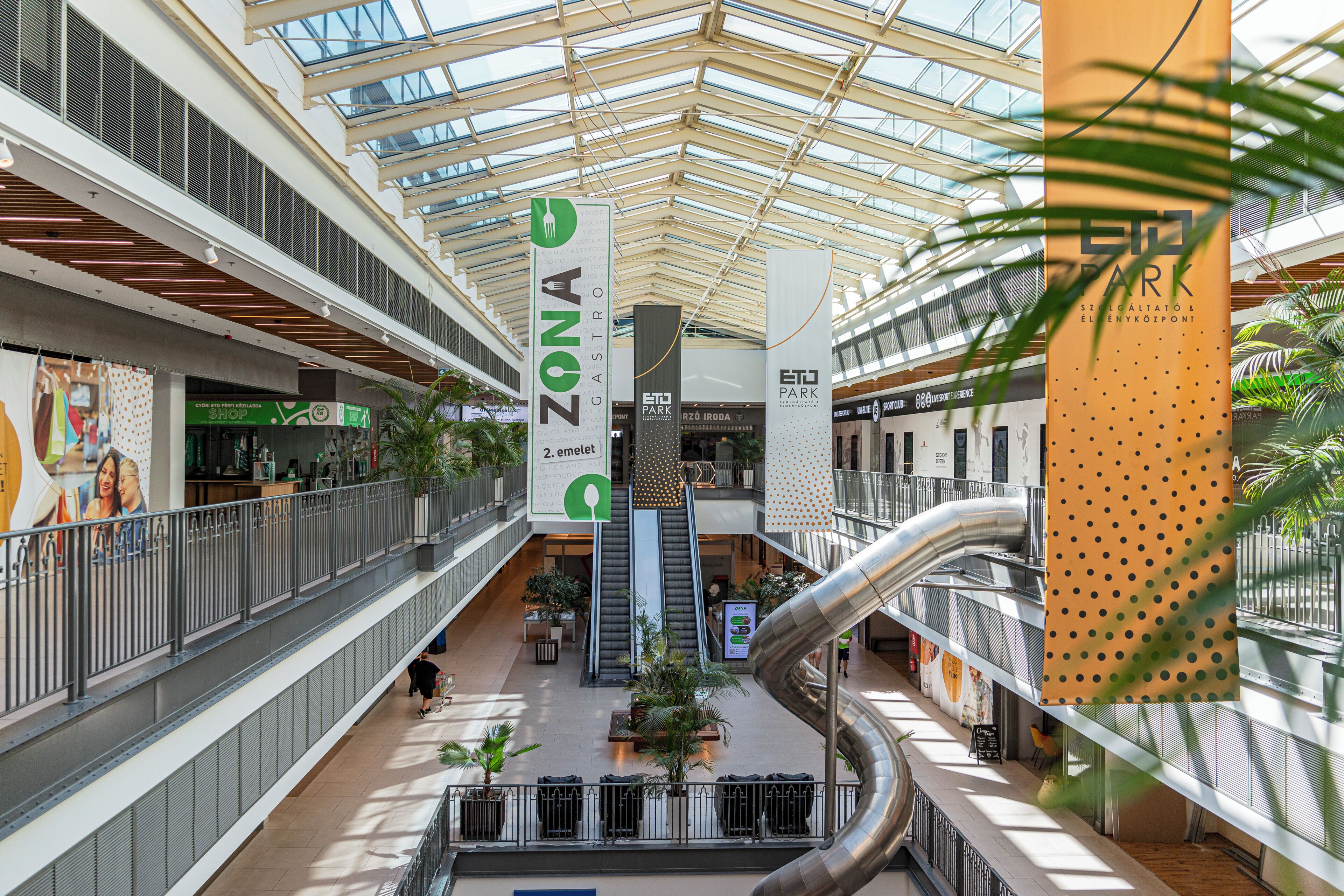 Un centro comercial de varios niveles con un atrio central, escaleras mecánicas y diversas tiendas.