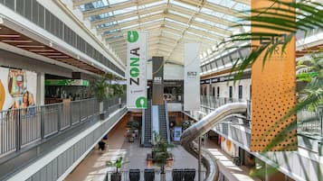 Un centro comercial de varios niveles con un atrio central, escaleras mecánicas y diversas tiendas.