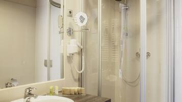 A modern bathroom with a glass-enclosed shower, a white sink, and a mirror.