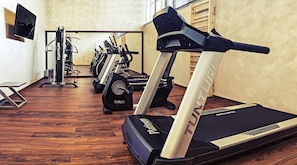 Un gimnasio con cintas de correr, bicicletas estáticas y máquinas de pesas.