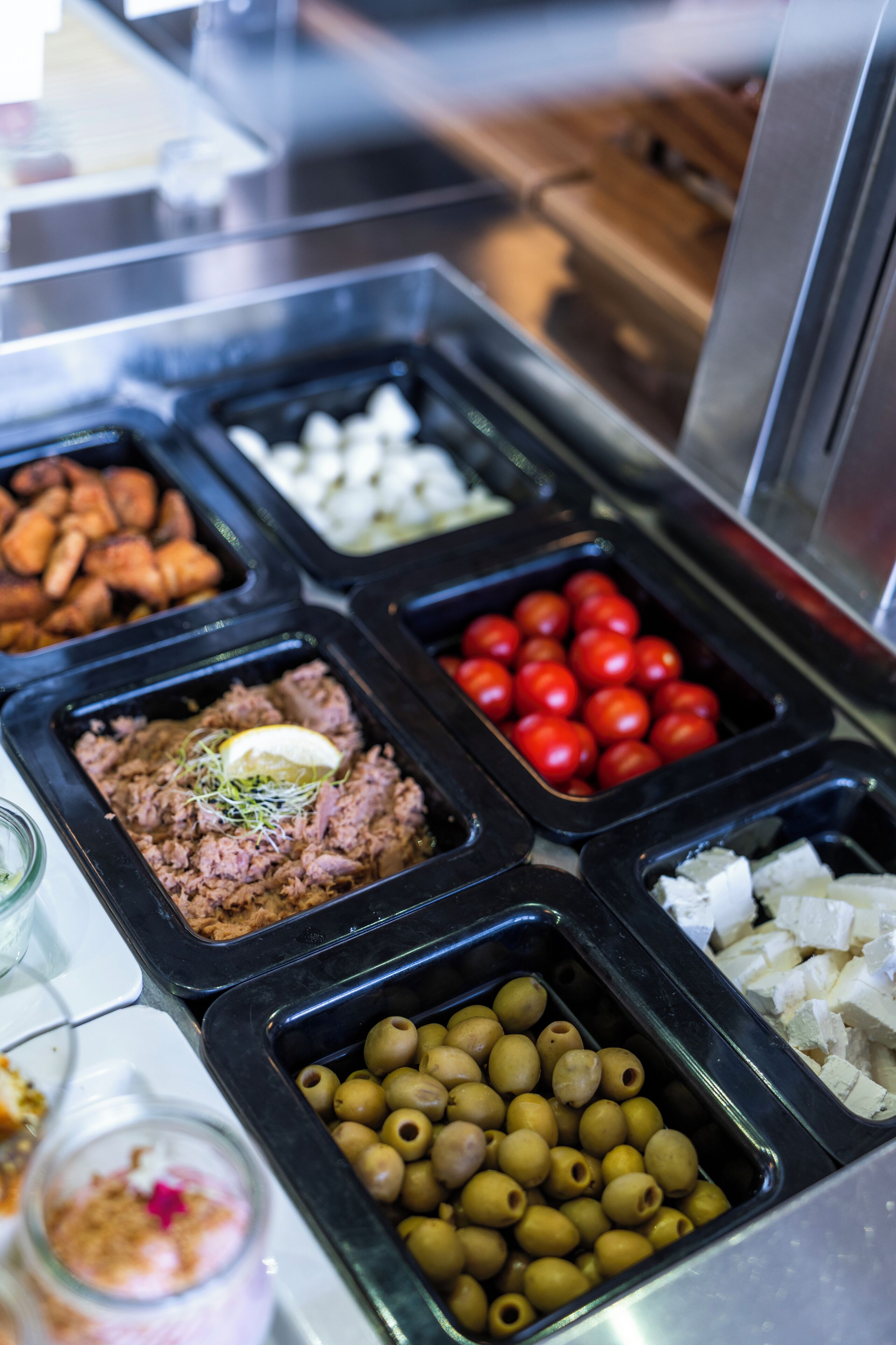 A buffet with various food options including meat, cheese, olives, and tomatoes.