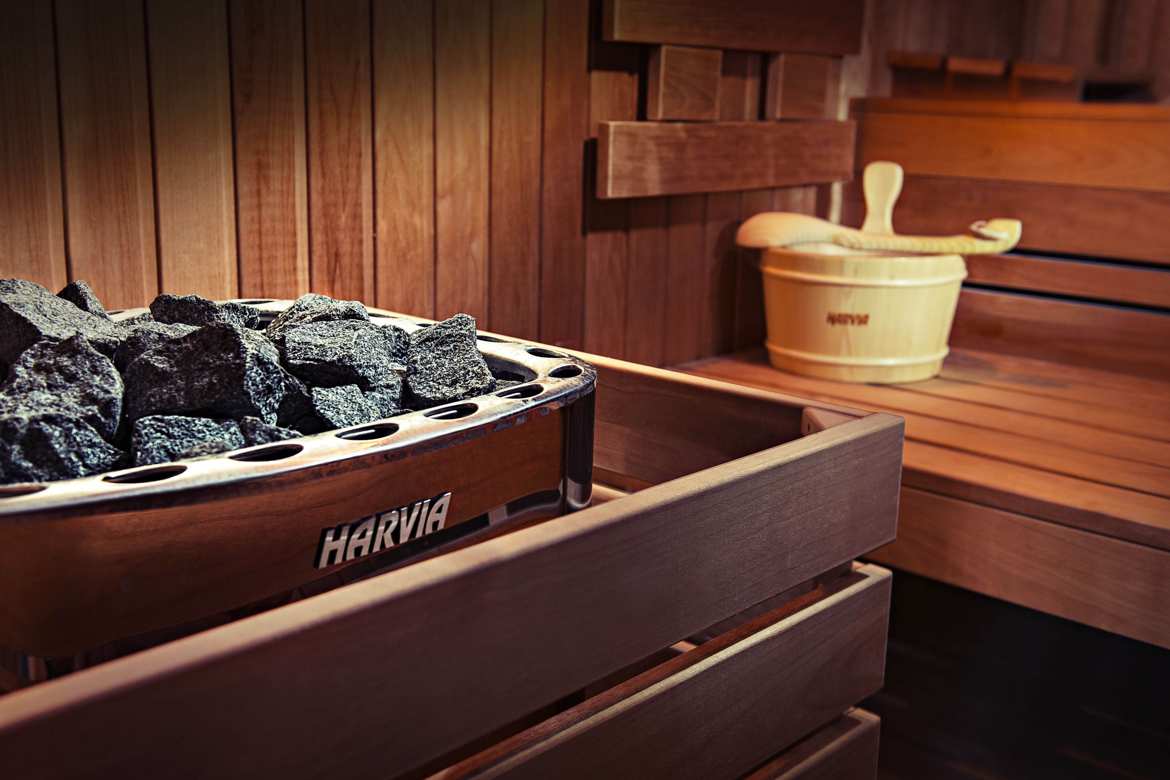 A sauna with a wooden bench, a charcoal bin, and a wooden bucket.