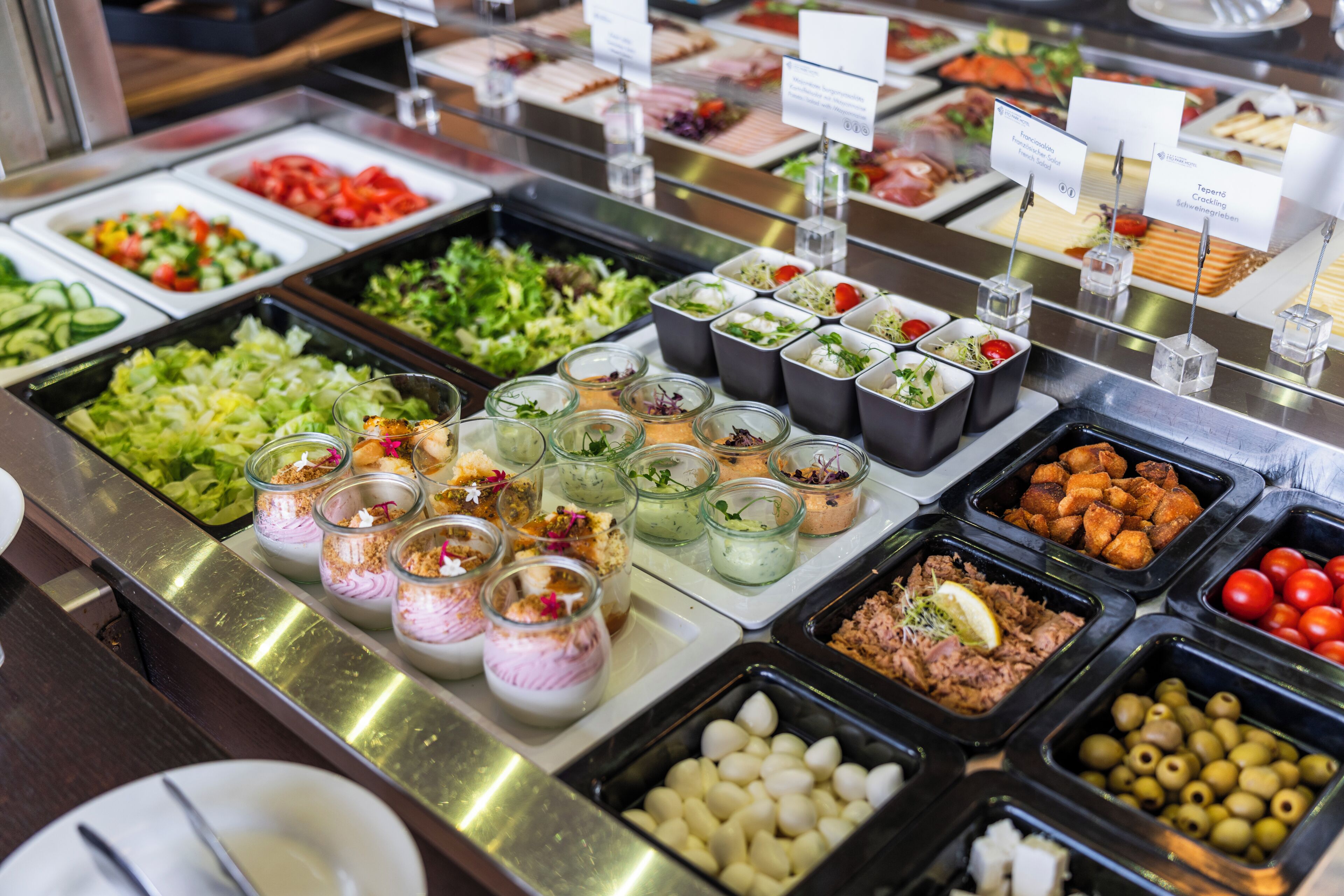 Un bufé con diversas opciones de comida, incluyendo ensaladas, carnes y postres.