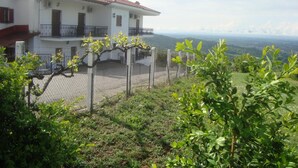 Una casa de dos pisos con techo de tejas rojas, un balcón y vistas del paisaje circundante.