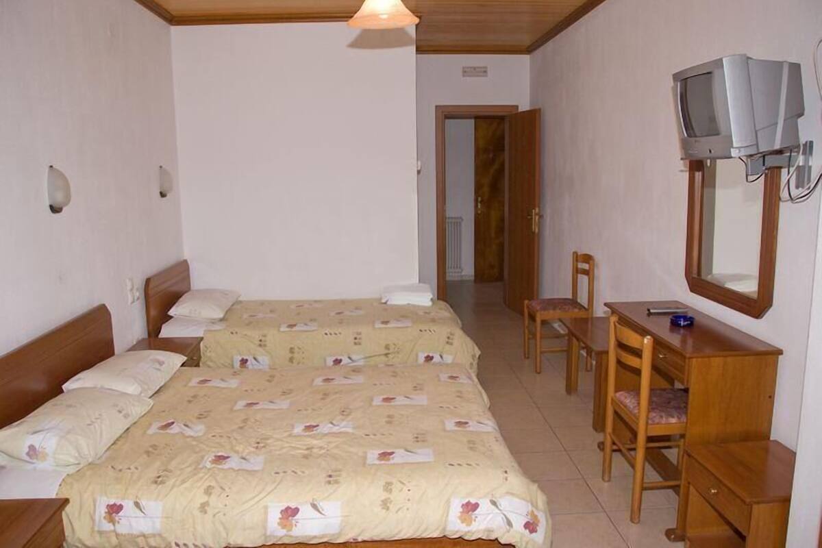 A room with two beds, a desk, a chair, a television, and a mirror.