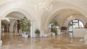 Un amplio vestíbulo con techos abovedados, un candelabro y plantas en macetas.