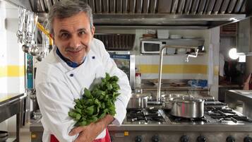 A chef in a professional kitchen holding fresh herbs.