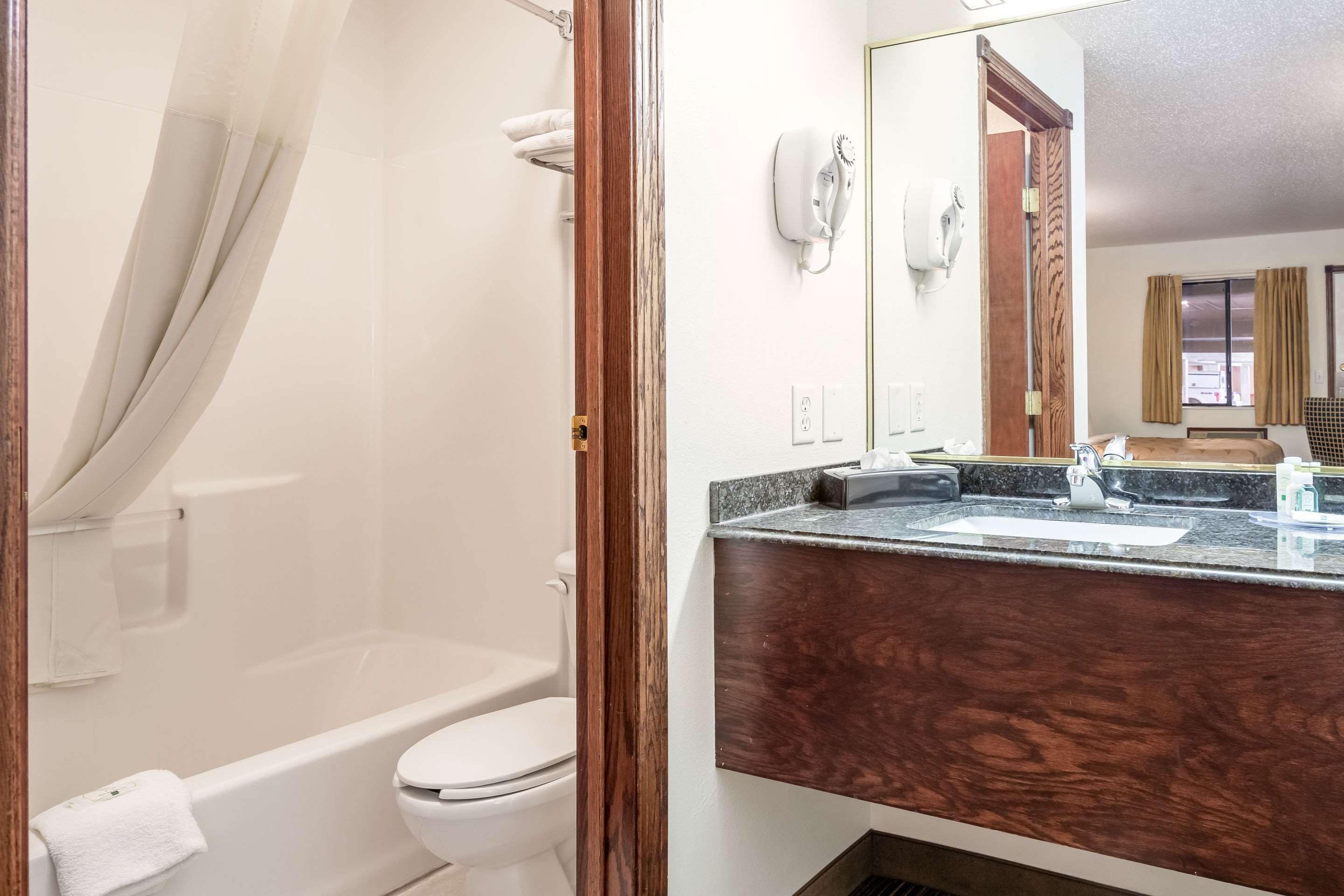 Een badkamer met een bad, toilet en een wastafel met spiegel.