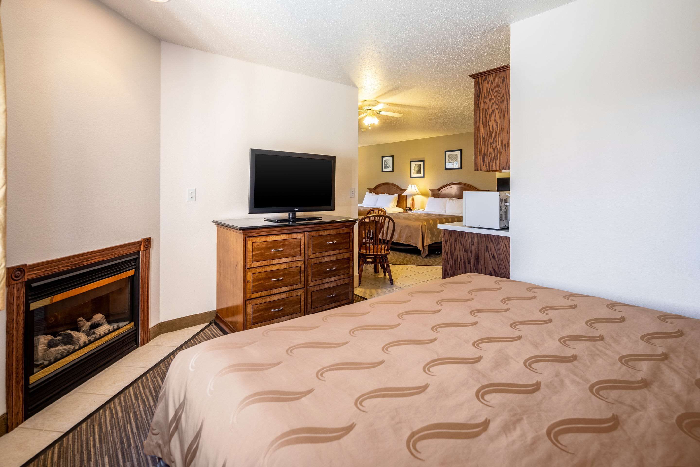 Habitación de hotel con cama, televisión, escritorio y chimenea.