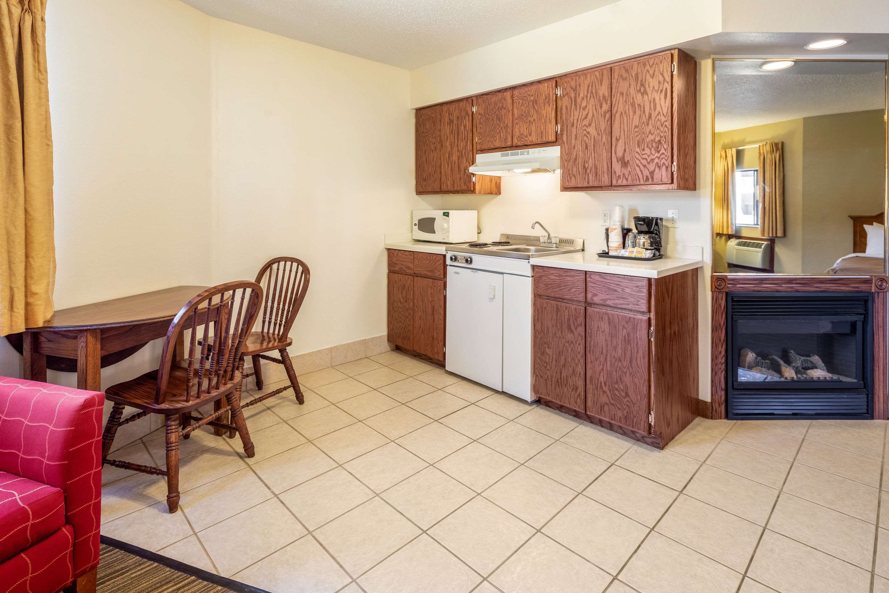 A compact kitchen with wooden cabinets, a microwave, a stove, and a coffee maker.