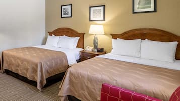Una habitación de hotel con dos camas, una mesita de noche con lámpara y cuadros en la pared.