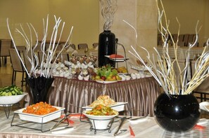 A buffet table with various dishes, including salads, vegetables, and a hot grill station.
