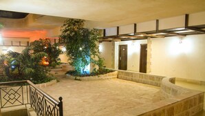 A stone-floored courtyard with a metal railing, a large tree, and a staircase leading to an upper level. - Manger Square Hotel (Bethlehem)