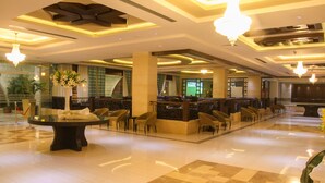 A spacious lobby with a checkered floor, a reception desk, and multiple seating areas. - Manger Square Hotel (Bethlehem)